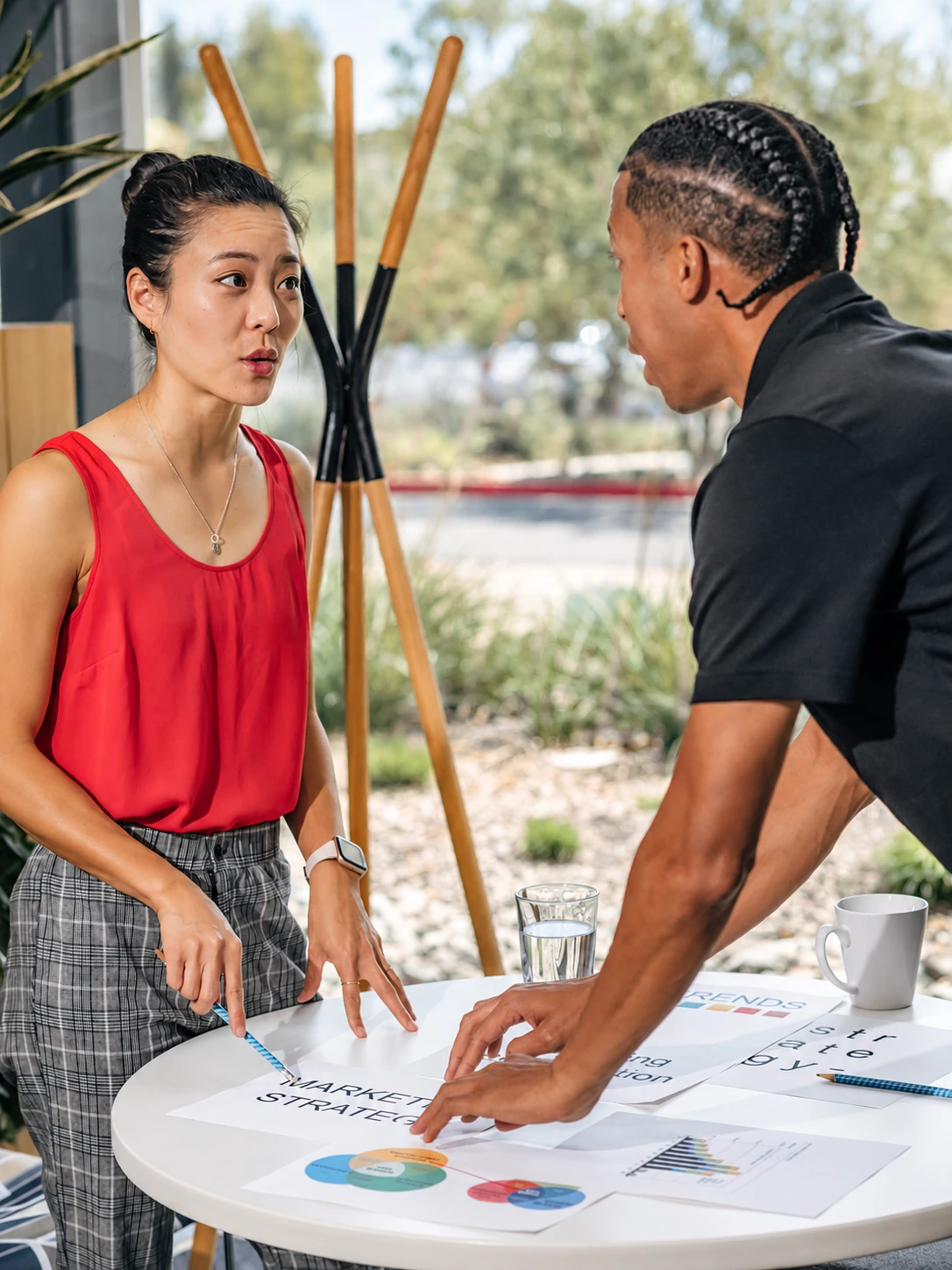 Two colleagues discussing marketing strategy and pointing to papers on a table.