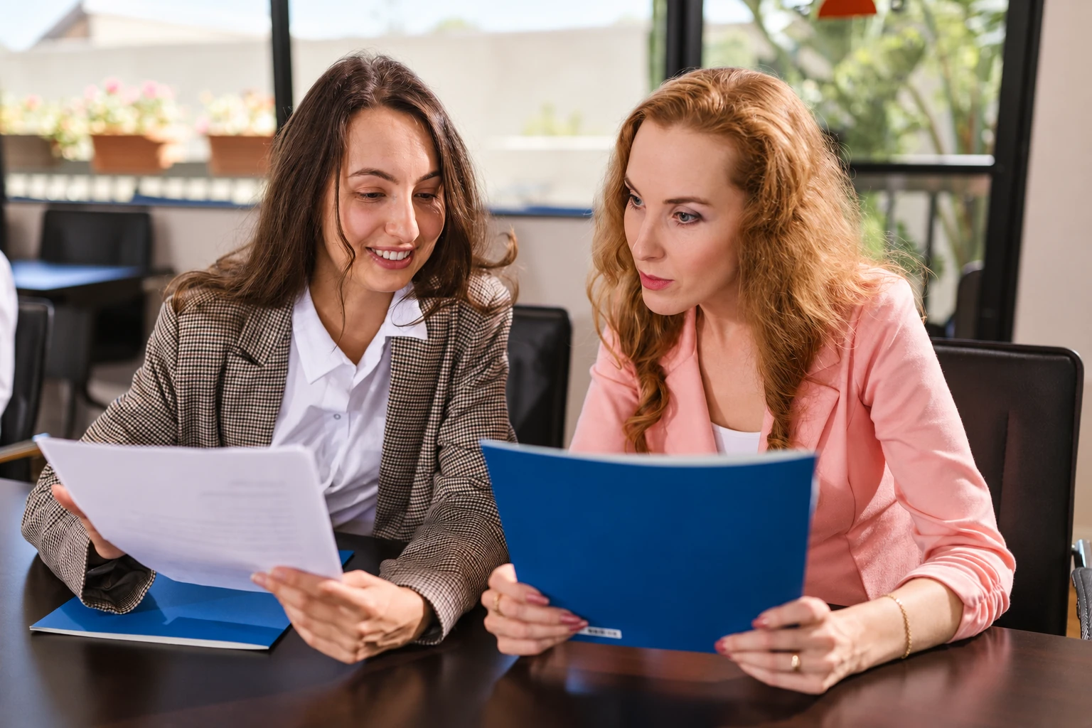 Two colleagues comparing documents together at a table.
